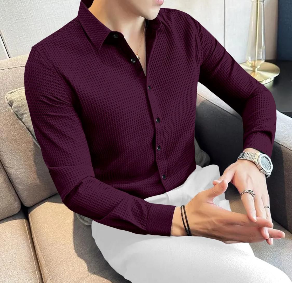 Person wearing a maroon textured shirt sitting on a couch.