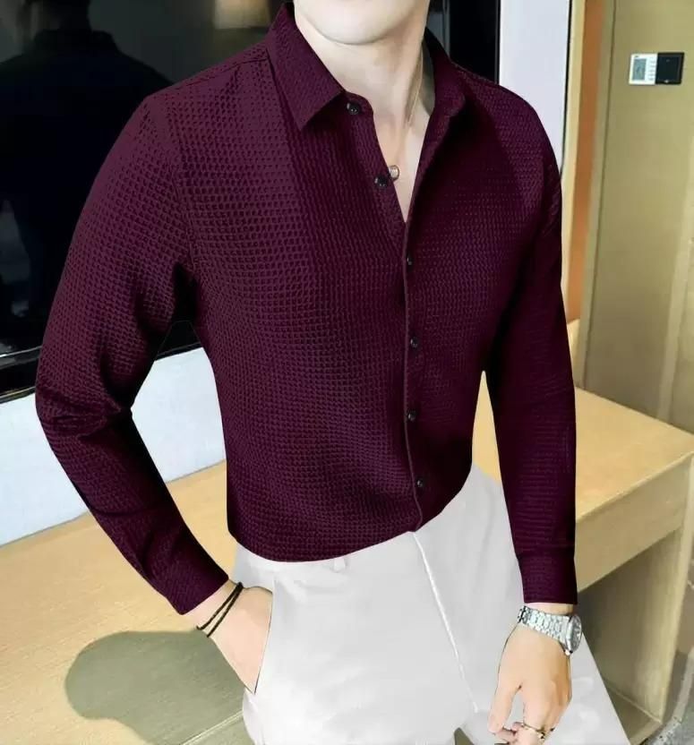 Person wearing a maroon textured shirt with white pants in an indoor setting
